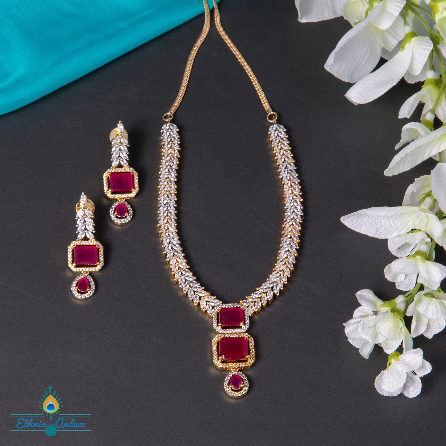 Mirra cubic zirconia jewelry set featuring a gold and silver tone necklace with ruby-colored stones and matching earrings.