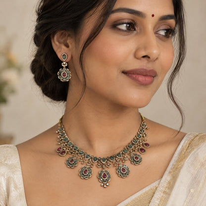 Indian woman wearing a bib-style necklace and matching drop earrings with floral faceted stones.