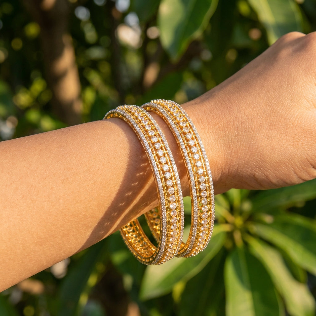 Petite Indian woman's wrist adorned with a delicate gold-finished Teji CZ bangle featuring tiny cubic zirconia stones sparkling in natural daylight.