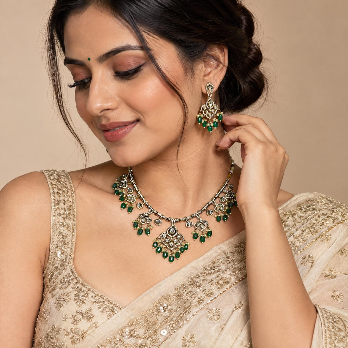 Close-up of an Indian model wearing a sophisticated kundan bangle with emerald green beads on her wrist in a studio setting.
