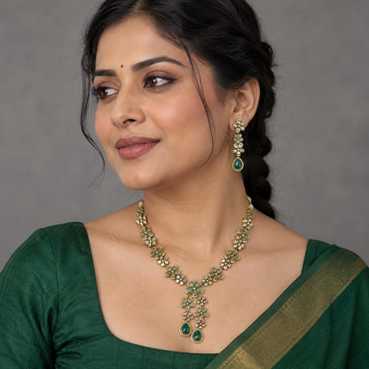 Indian woman wearing flower-shaped kundan dangle earrings with a plain emerald green blouse.