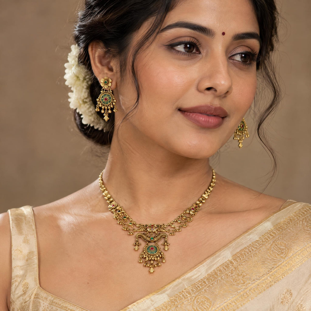 Indian model wearing a gold necklace with ruby and emerald accents in a close-up portrait.