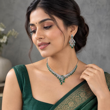 Indian model wearing a sparkling silver and green cubic zirconia necklace set in a minimalist studio setting.