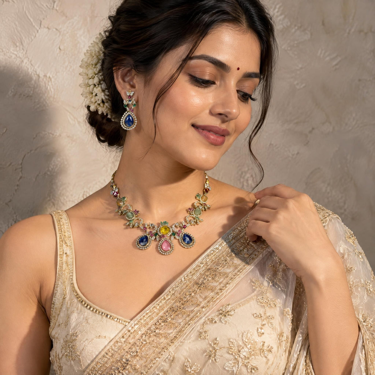 Indian model wearing a complete multi-colored gemstone necklace set against a textured plaster wall.