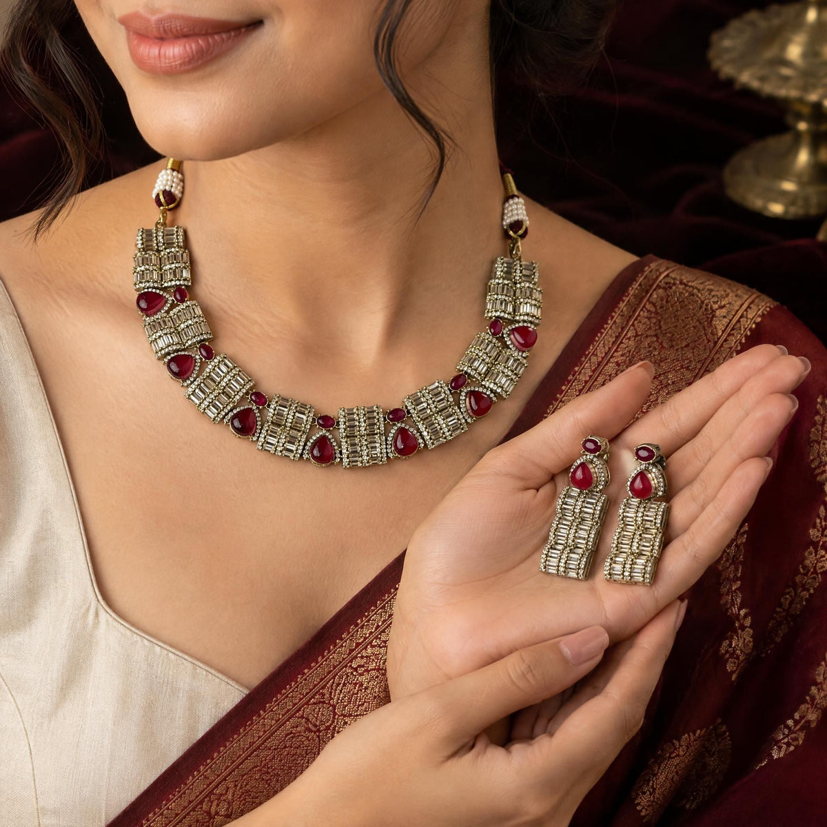Close-up of Sufiya American diamond drop earrings held in a hand against a dark velvet background.